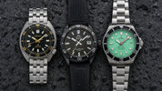 Seiko Prospex Turtle, Orient Mako, and Ratio FreeDiver flat-lay on dark wet surface